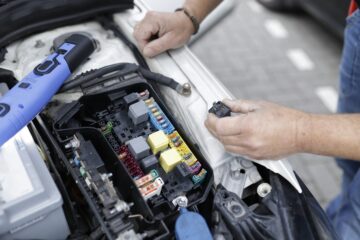 Meccanico al lavoro sul motore auto in officina con componenti in evidenza