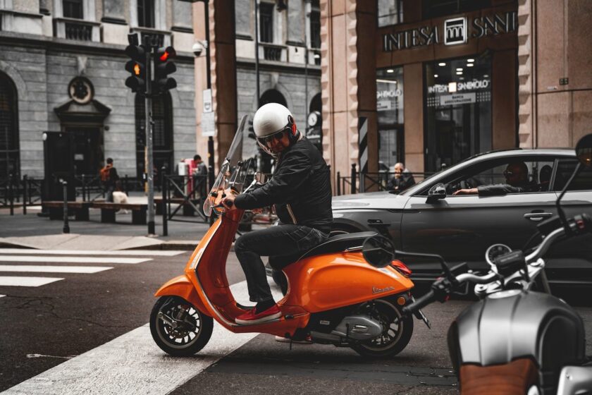 Uomo alla guida di uno scooter 150cc in centro città, con casco