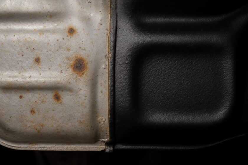 Dettaglio del sottoscocca auto con ruggine su una parte e trattamento protettivo sull’altra