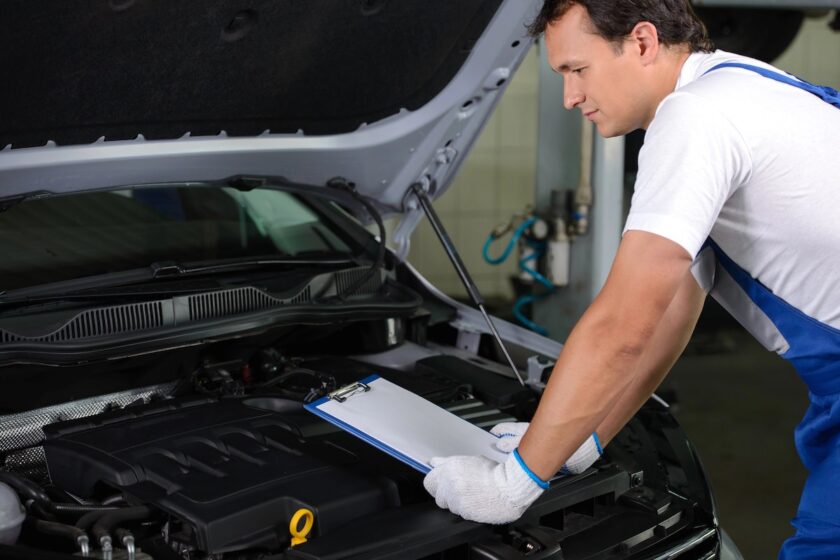 Meccanico che ispeziona il vano motore per individuare la causa del fischio auto