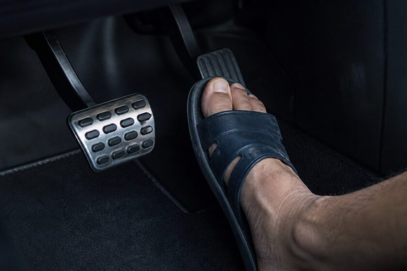 piede con ciabatte preme pedale auto evidenziando il controllo