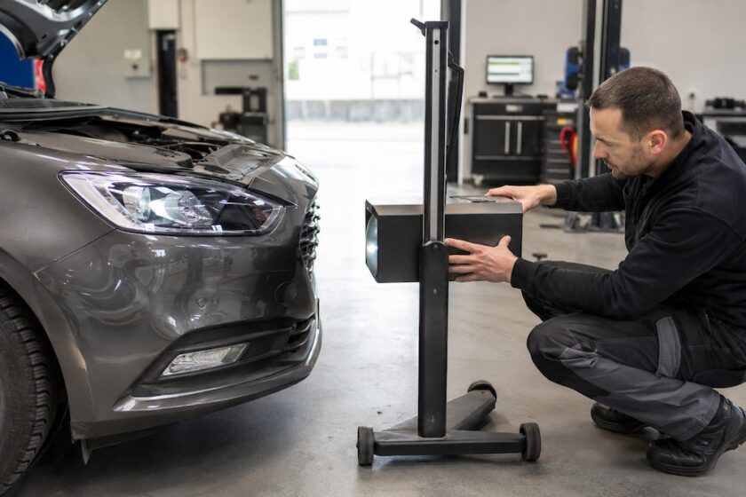 Meccanico controlla il faro di un’automobile con un regolafari professionale