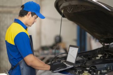 Tecnico che osserva il contachilometri di un’auto ferma e annota il valore su una scheda.